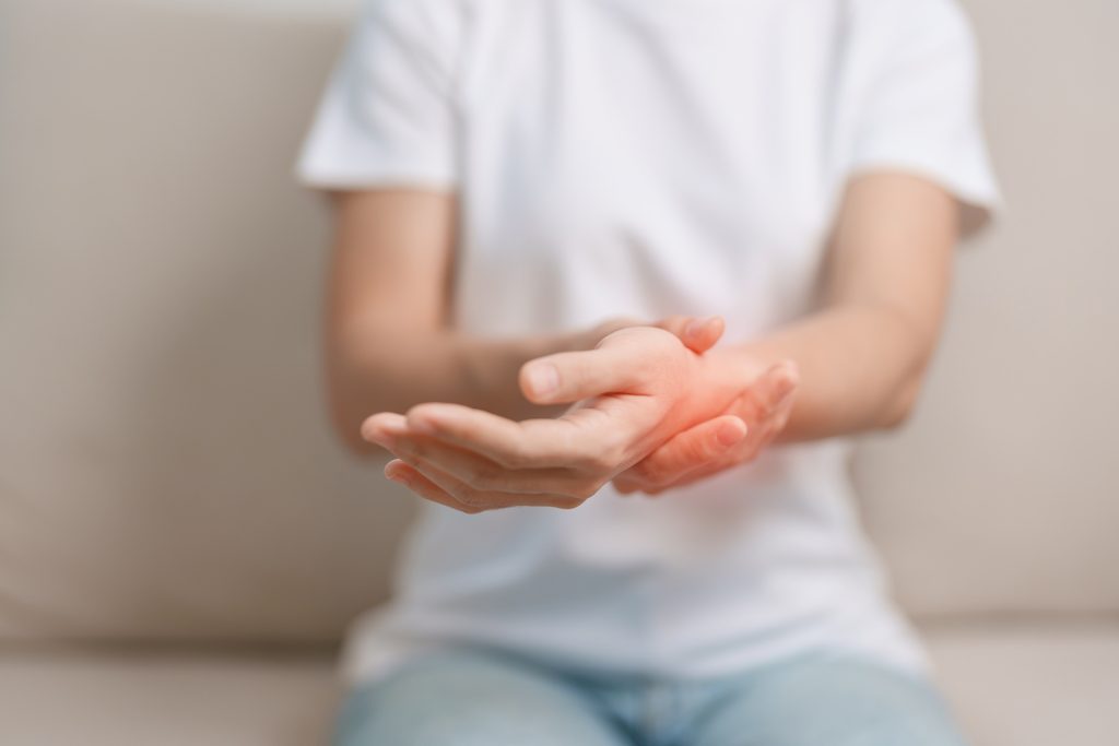 Woman having wrist pain during sitting on sofa at home