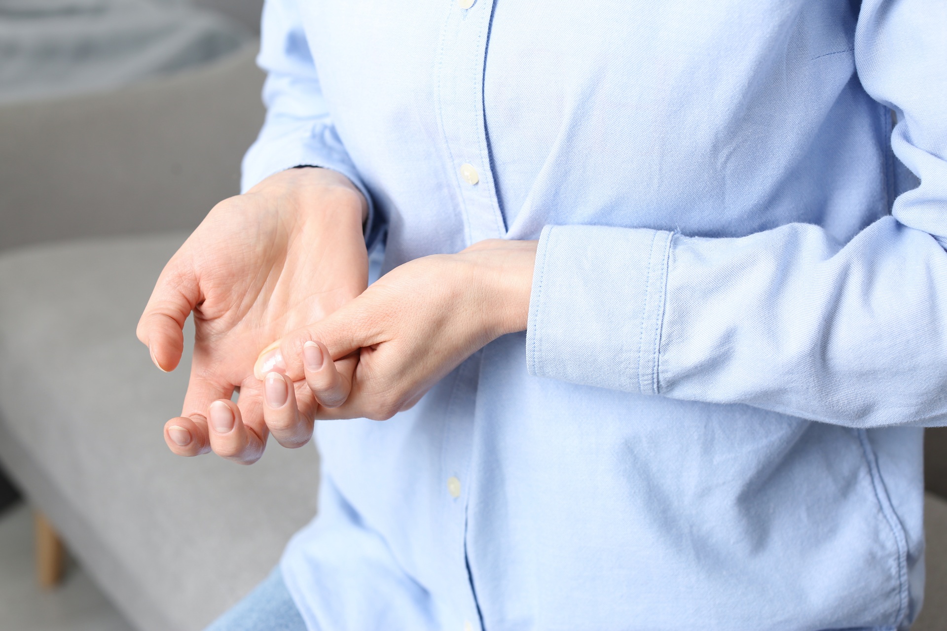Woman suffering from trigger finger on sofa, closeup