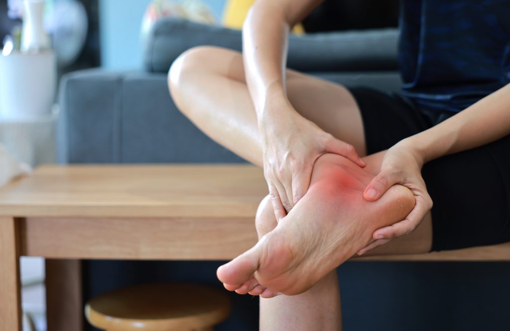 Woman massaging her painful knee and ankle with red highlight. Knee osteoarthritis, ankle sprain, joint inflammation and injury concept for health care, physical therapy and medical treatment.
