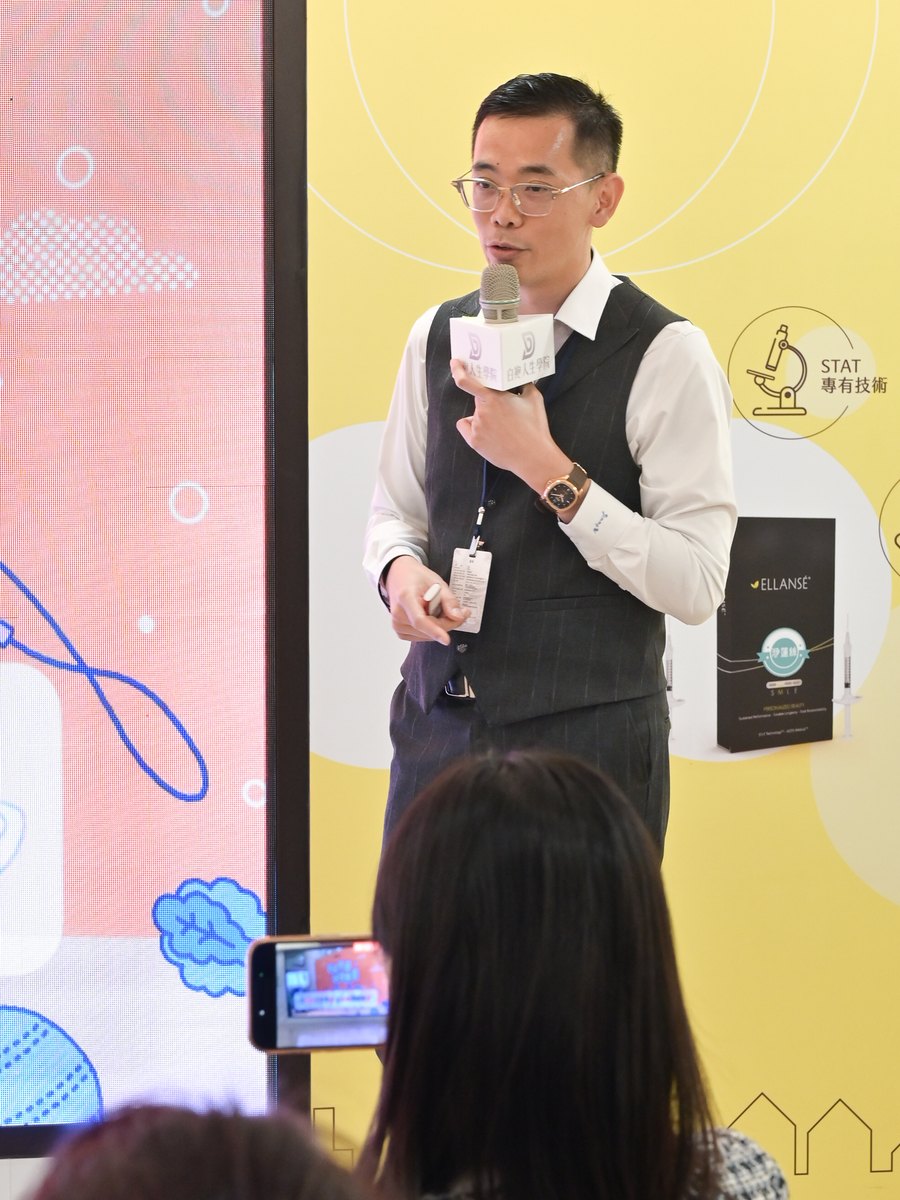 吳政誼醫師手持麥克風在華山論劍台北站分享,台下有人舉起手機拍攝投影片