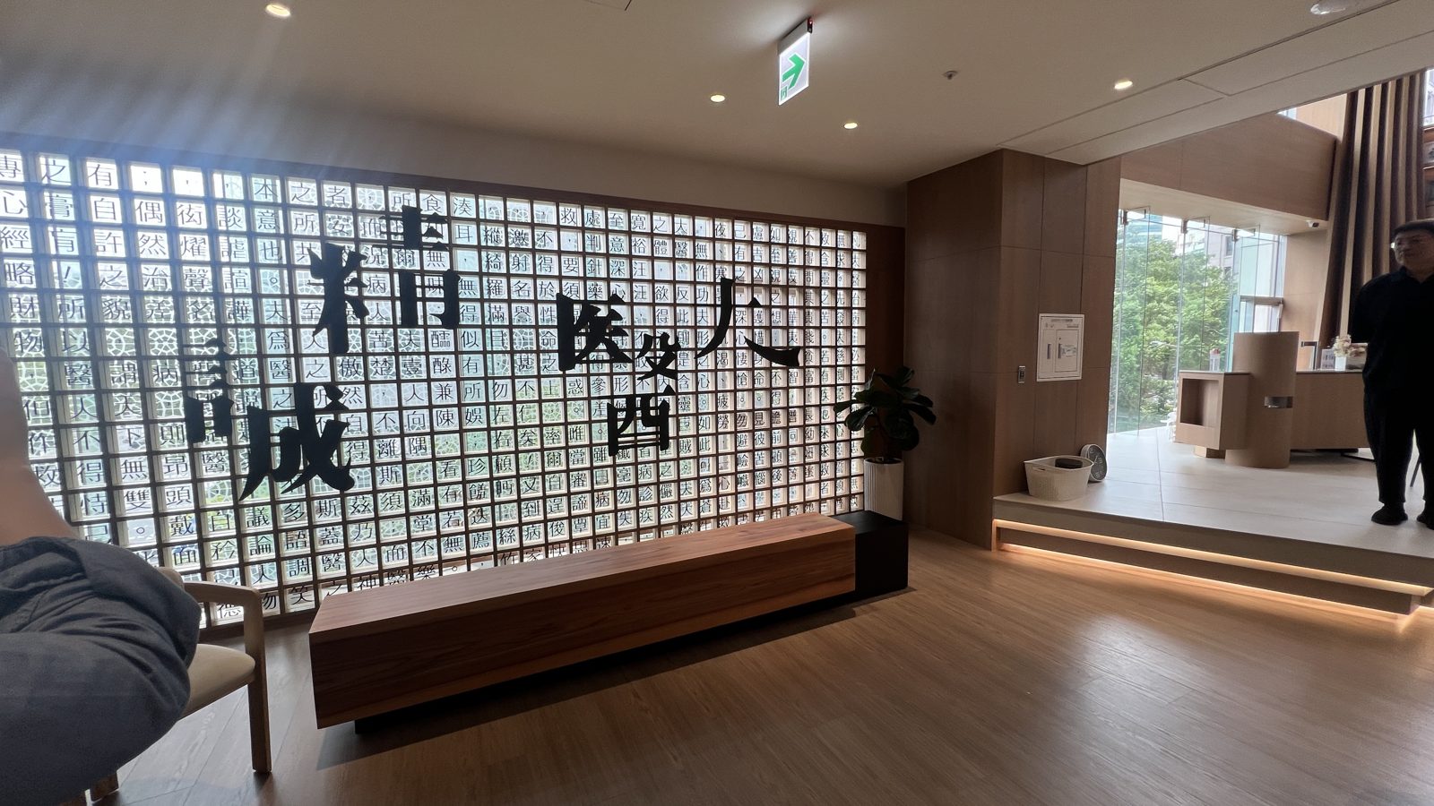 馬光中醫信義旗艦店大廳的「精誠醫人」字牆:一整面由字塊組成的透光牆,前方是一張長木凳