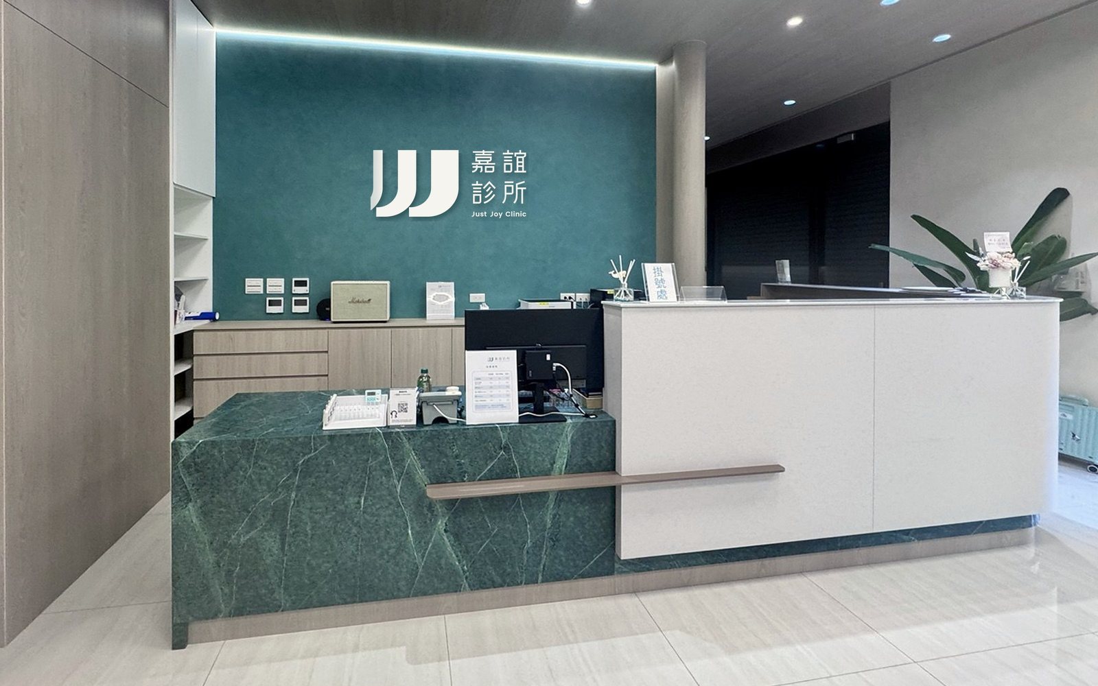 嘉誼診所櫃檯實景，後方形象牆上的標誌為示意，實際施工中